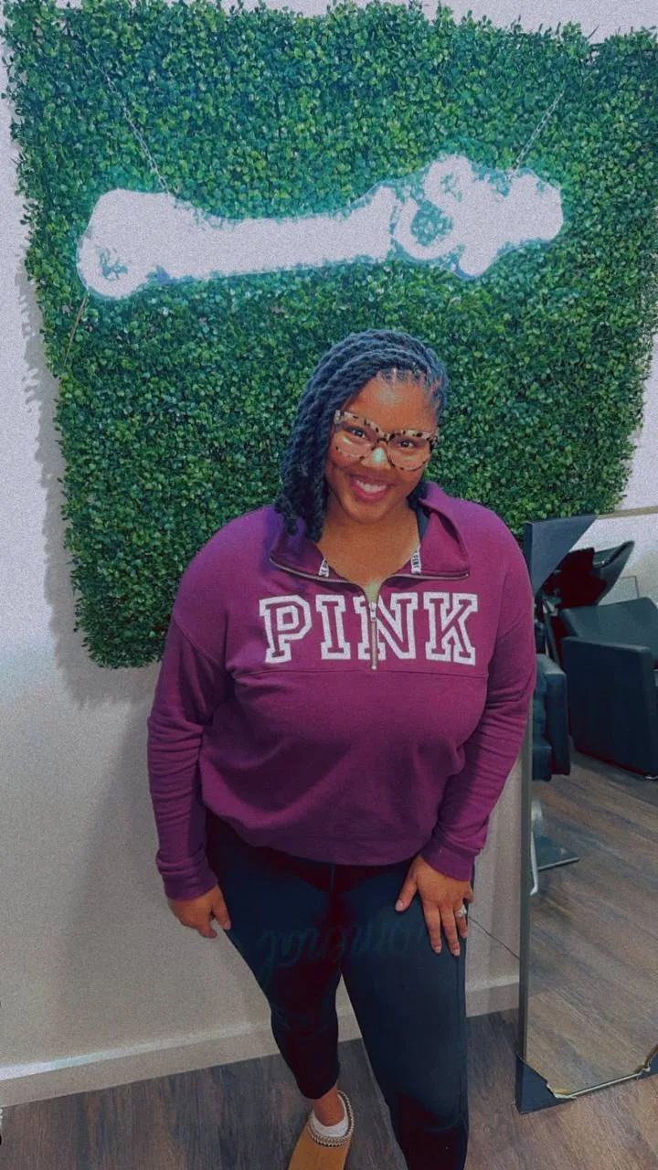 Smiling client in a PINK sweatshirt in front of the neon sign