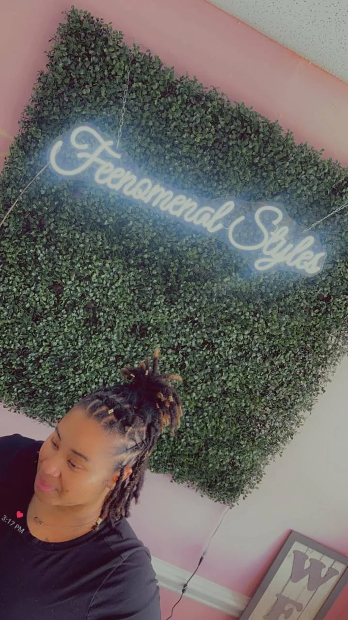 Client with locs styled up, in front of the neon sign