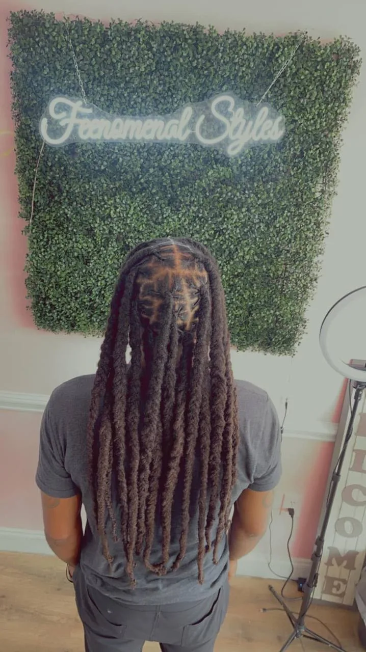 Back view of long locs in front of the neon Feenomenal Styles sign