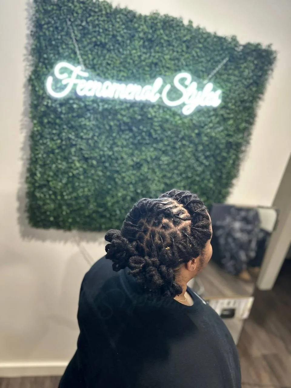 Locs gathered into an updo in front of the neon sign